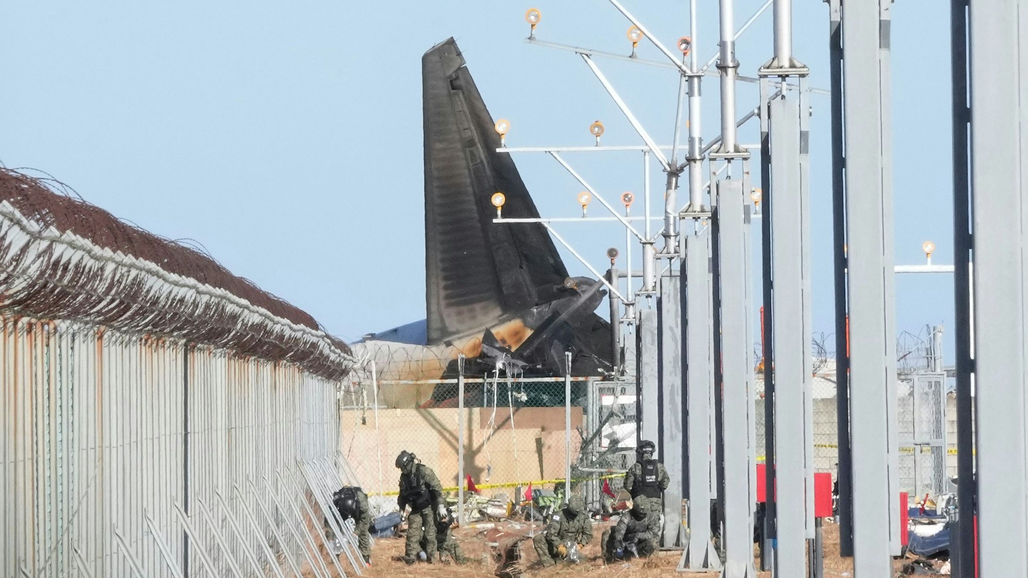 Eine verrußte Tragfläche ragt über eine Betonmauer.