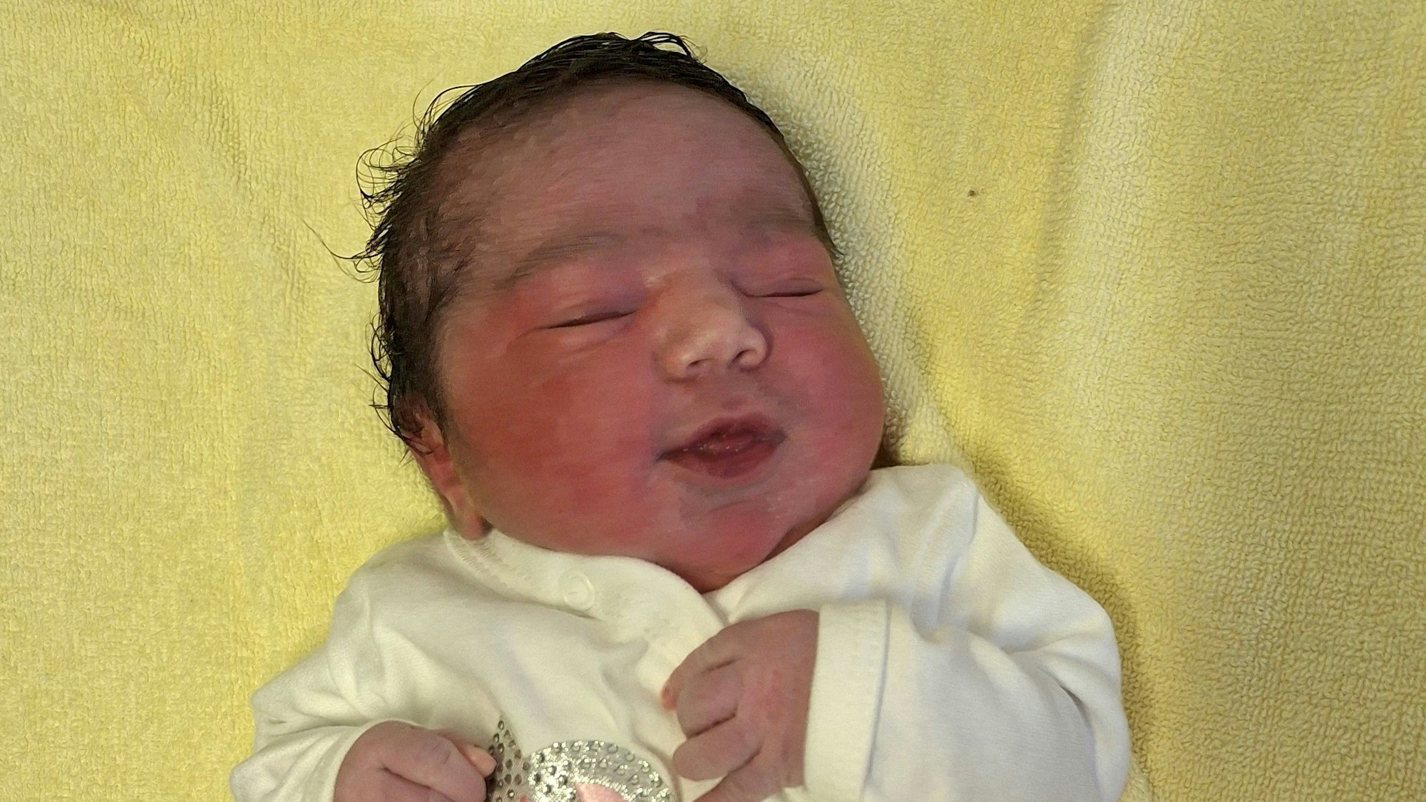 Das neugeborene Baby Hava liegt auf einer gelben Unterlage.