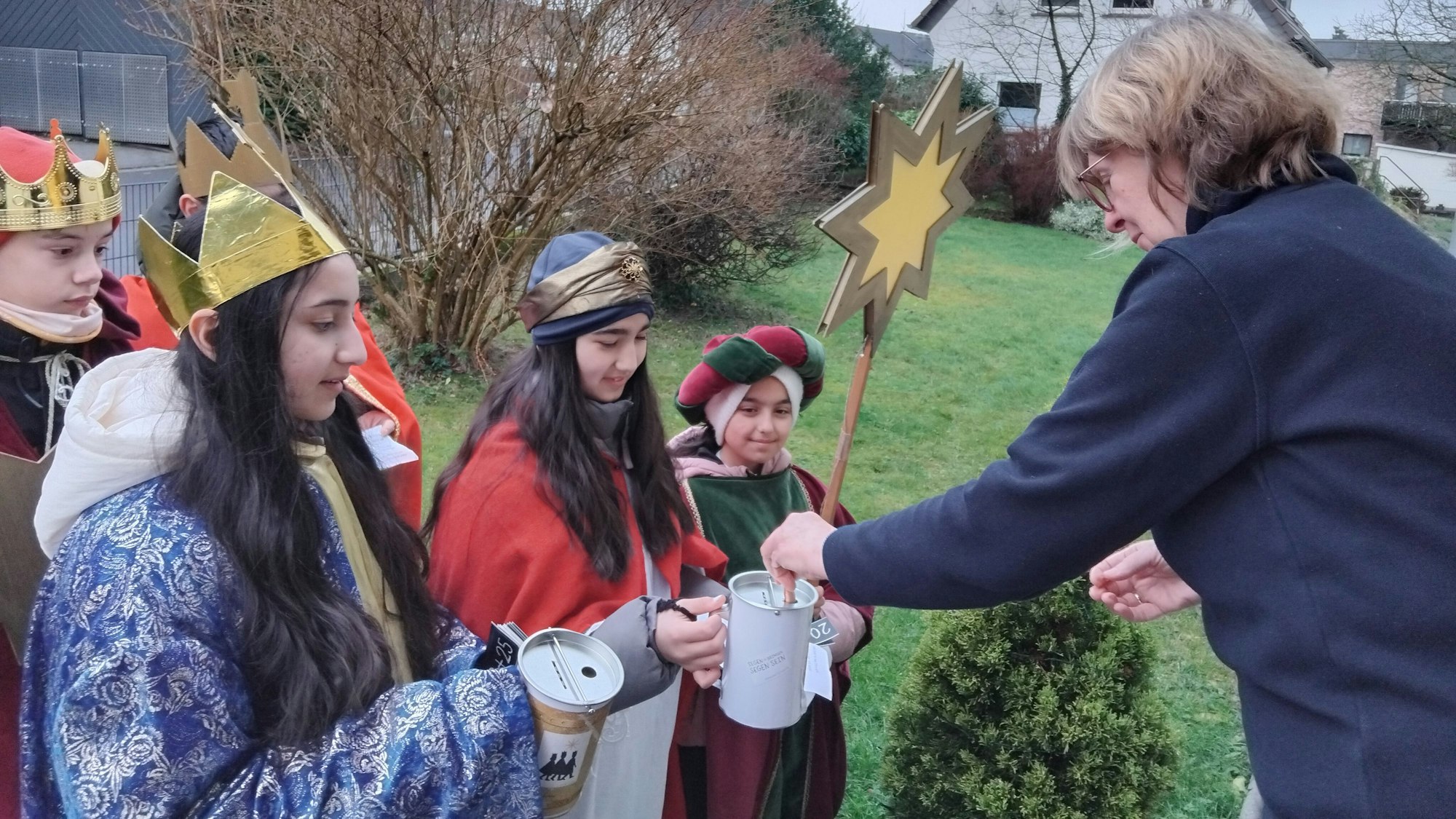 Eine Frau steckt einen Geldschein in die Sammeldose von Sternsingern
