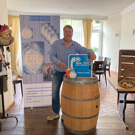 Hanns Udo Schild-Havenstein hat seine beiden Bücher und ein Schild aus Amerika auf einem Weinfass drapiert.