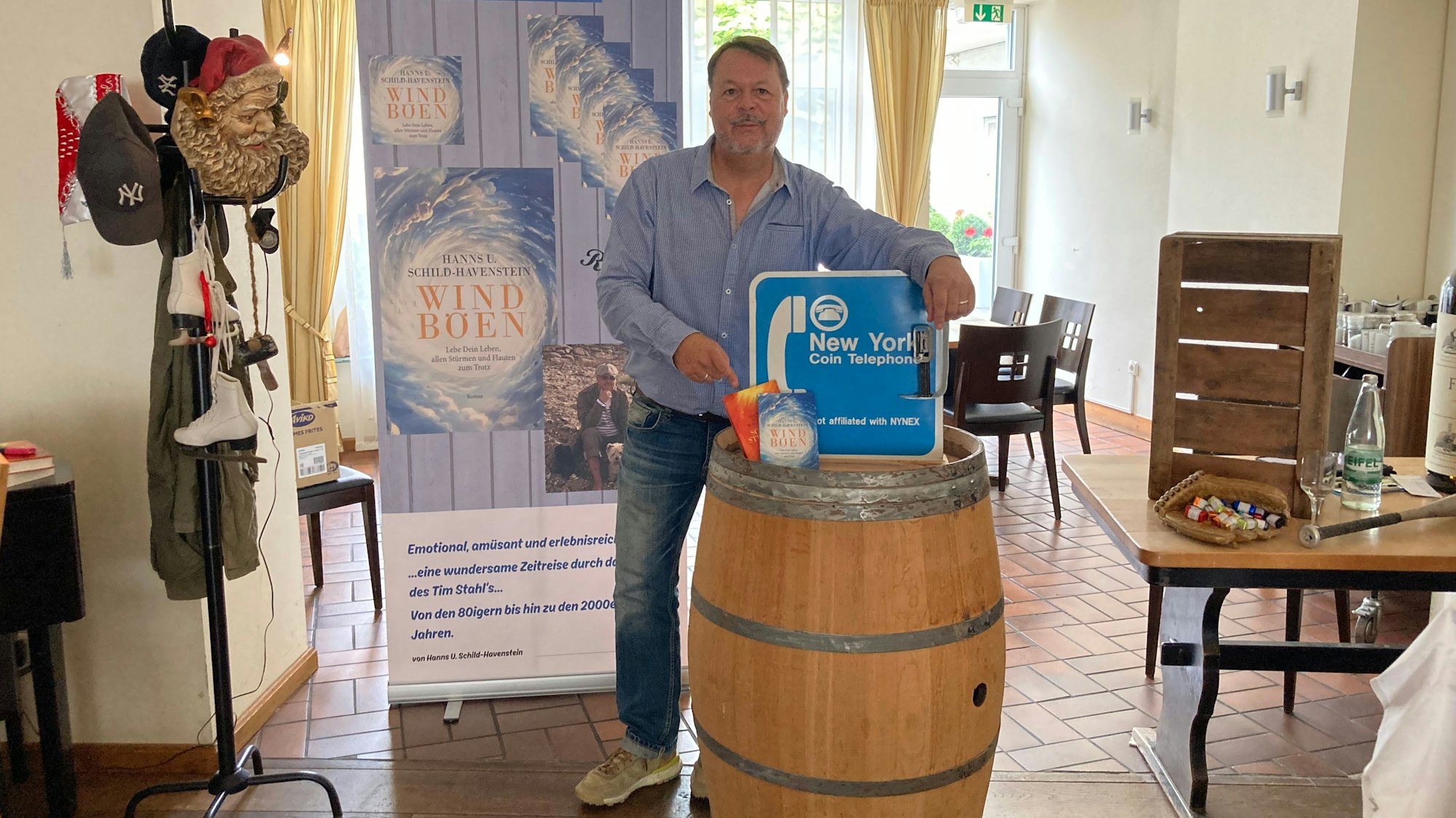 Hanns Udo Schild-Havenstein hat seine beiden Bücher und ein Schild aus Amerika auf einem Weinfass drapiert.