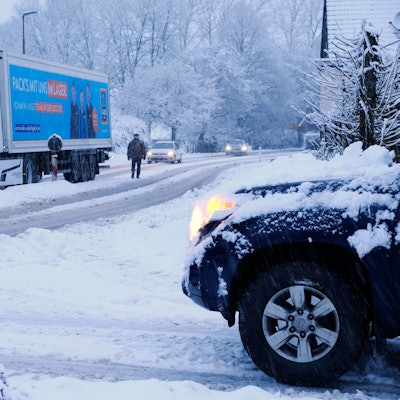 Ein Lastzug steckt auf einer winterlichen Straße in Nettersheim-Zingsheim wegen Eisglätte am Berg fest.