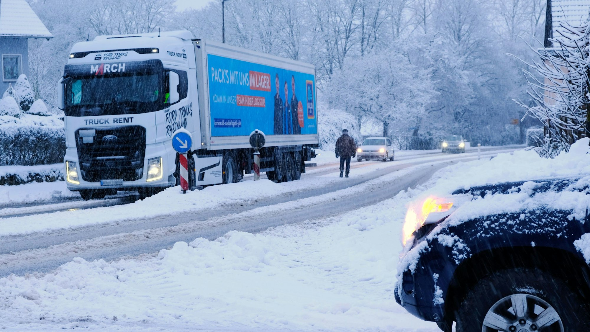 Ein Lastzug steckt auf einer winterlichen Straße in Nettersheim-Zingsheim wegen Eisglätte am Berg fest.