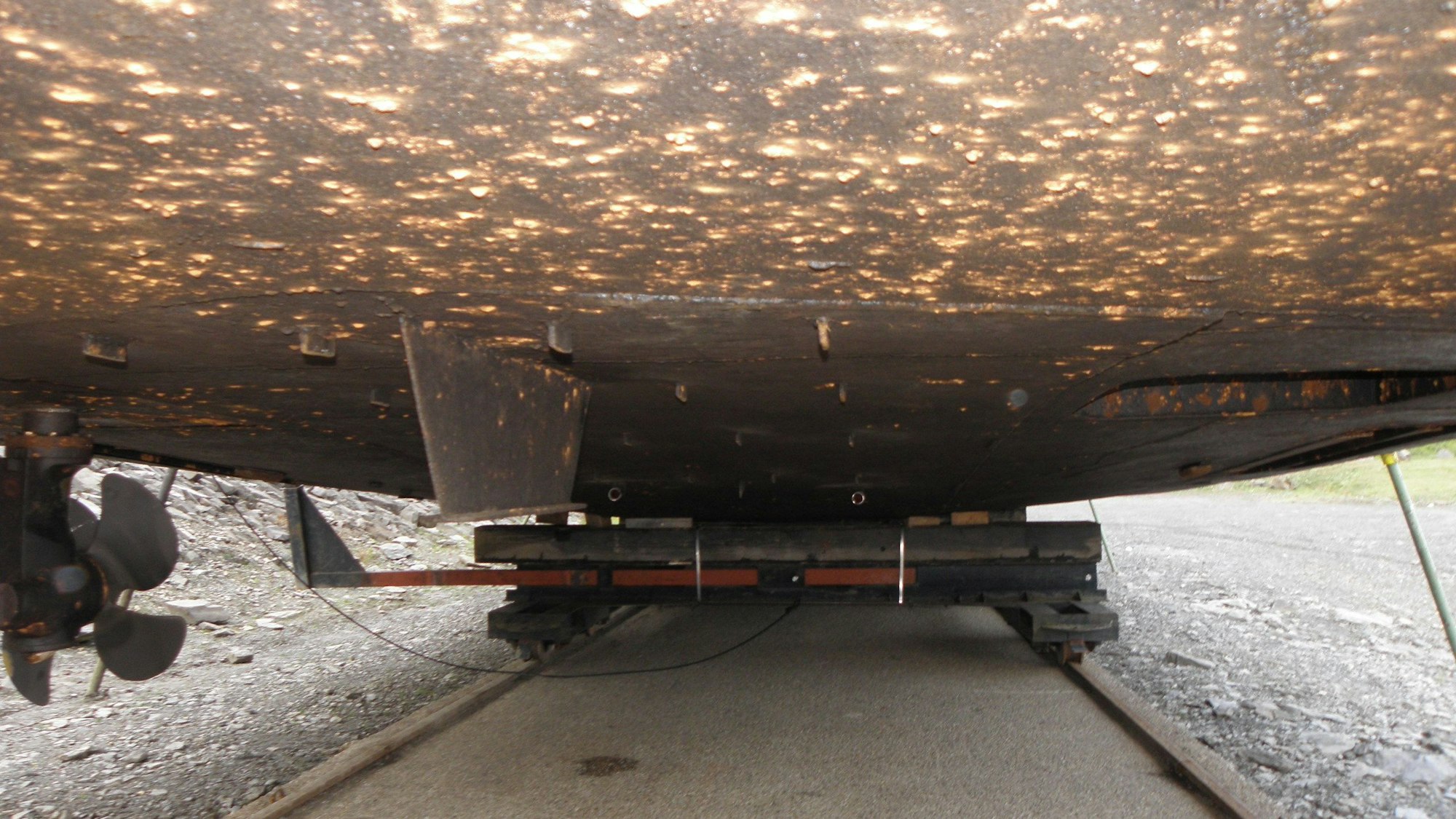 An der Unterseite des auf dem Trockendock liegenden Schiffs Aachen ist Rost zu erkennen. Auf der linken Seite ist die Schiffsschraube zu sehen.