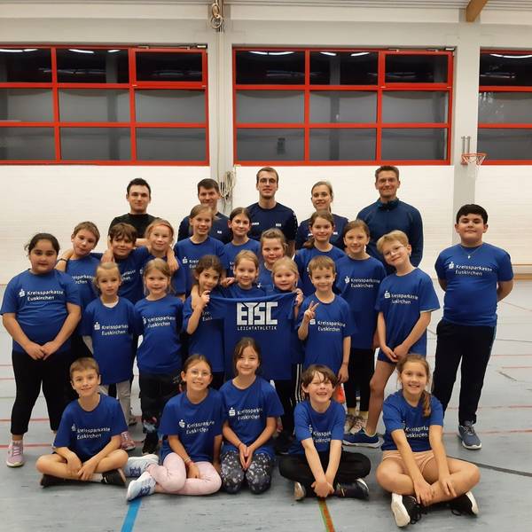 Kinder und Trainer der ETSC-Leichtathletikabteilungen stellen sich auf und halten ein Shirt mit der Aufschrift ETSC hoch.