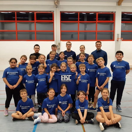 Kinder und Trainer der ETSC-Leichtathletikabteilungen stellen sich auf und halten ein Shirt mit der Aufschrift ETSC hoch.