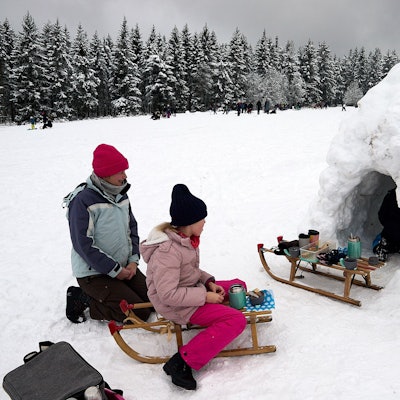 Die Familie hat es sich an der Eishöhle bequem gemacht, auf einem der beiden Schlitten stehen Getränke bereit.