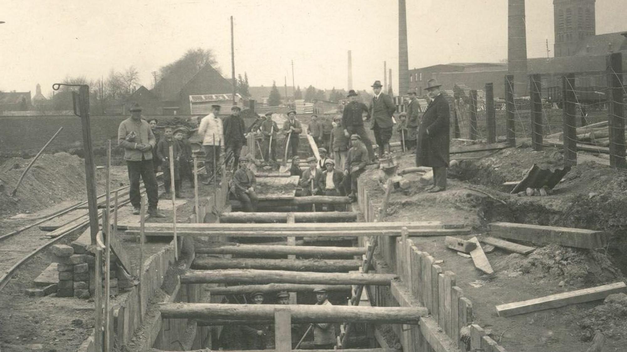 Auf dem historischen SW-Foto sind Bauarbeiter zu sehen, die einen Schacht frei legen.