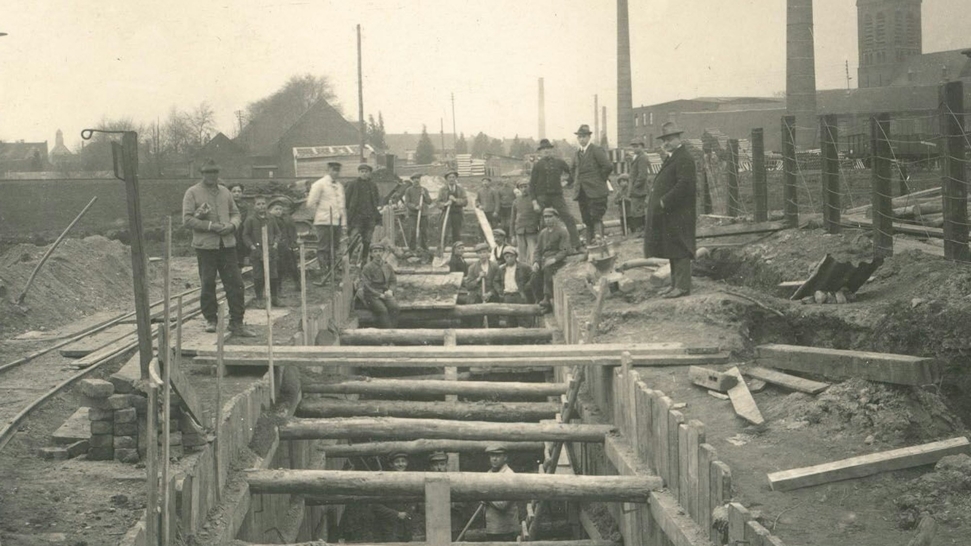 Auf dem historischen SW-Foto sind Bauarbeiter zu sehen, die einen Schacht frei legen.