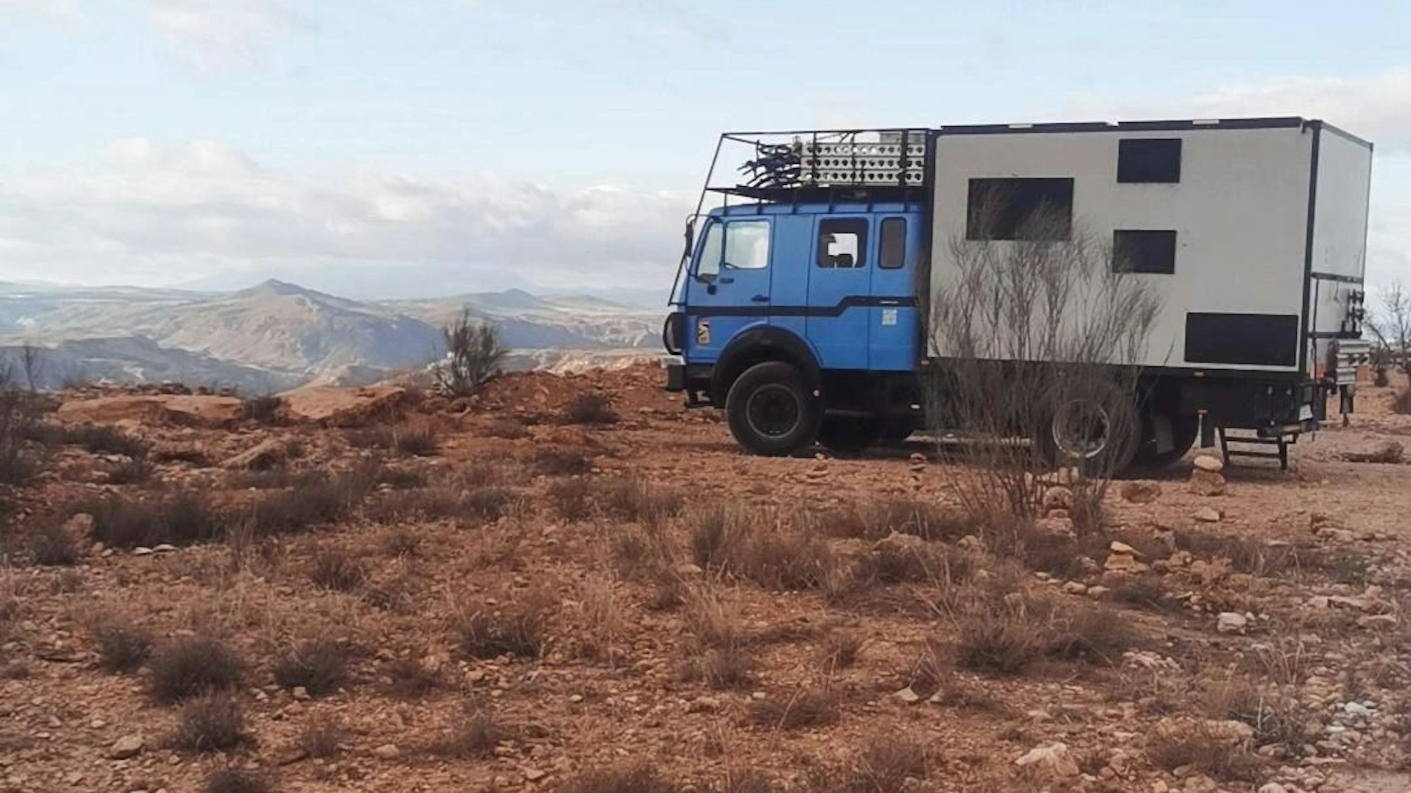 Ein blaues Expeditionsmobil in einer Landschaft.