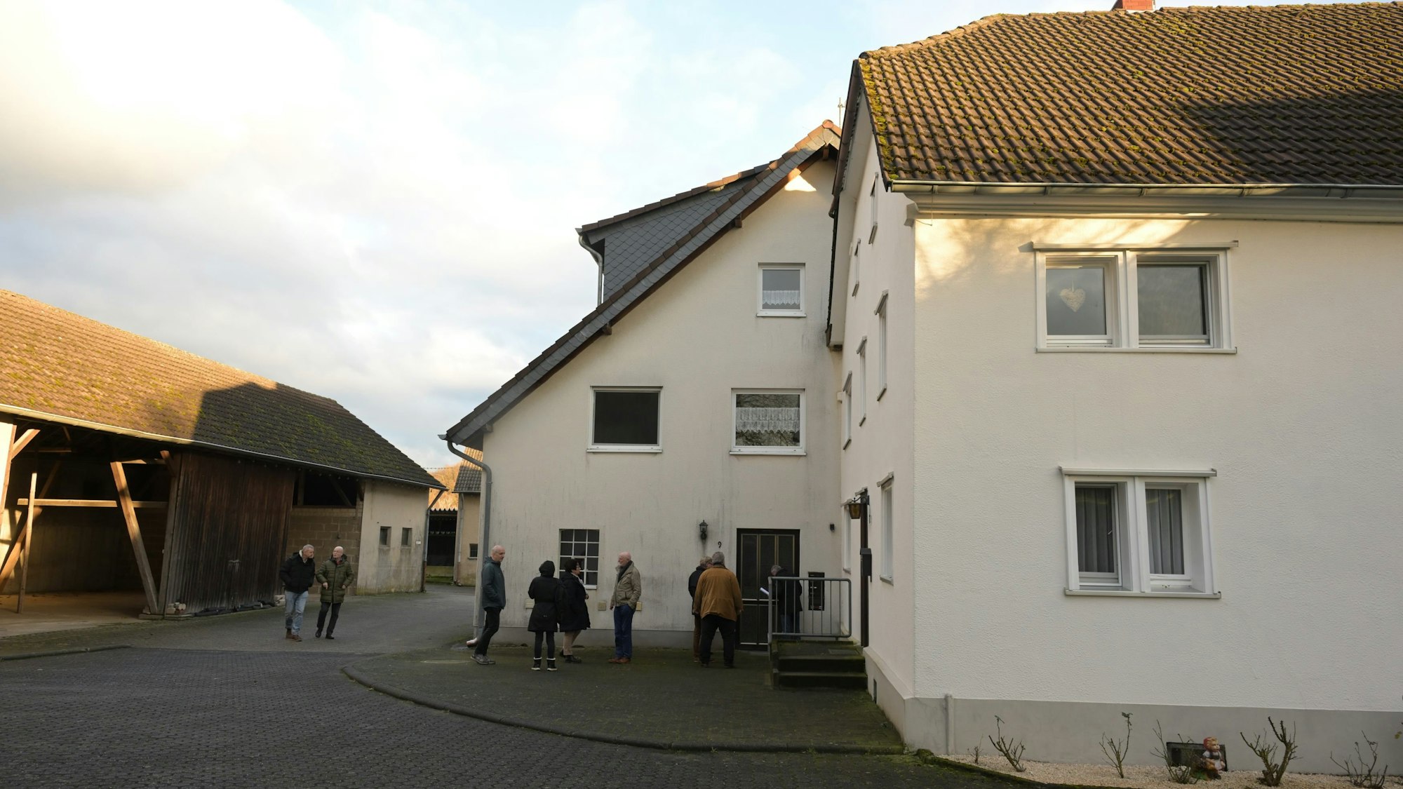 Ein Bauernhaus mit Hof und Scheune, davor stehen mehrere Besucher zur Besichtigung.