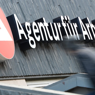 Zwei Männer gehen die Treppe zu einer Arbeitsagentur hinauf.