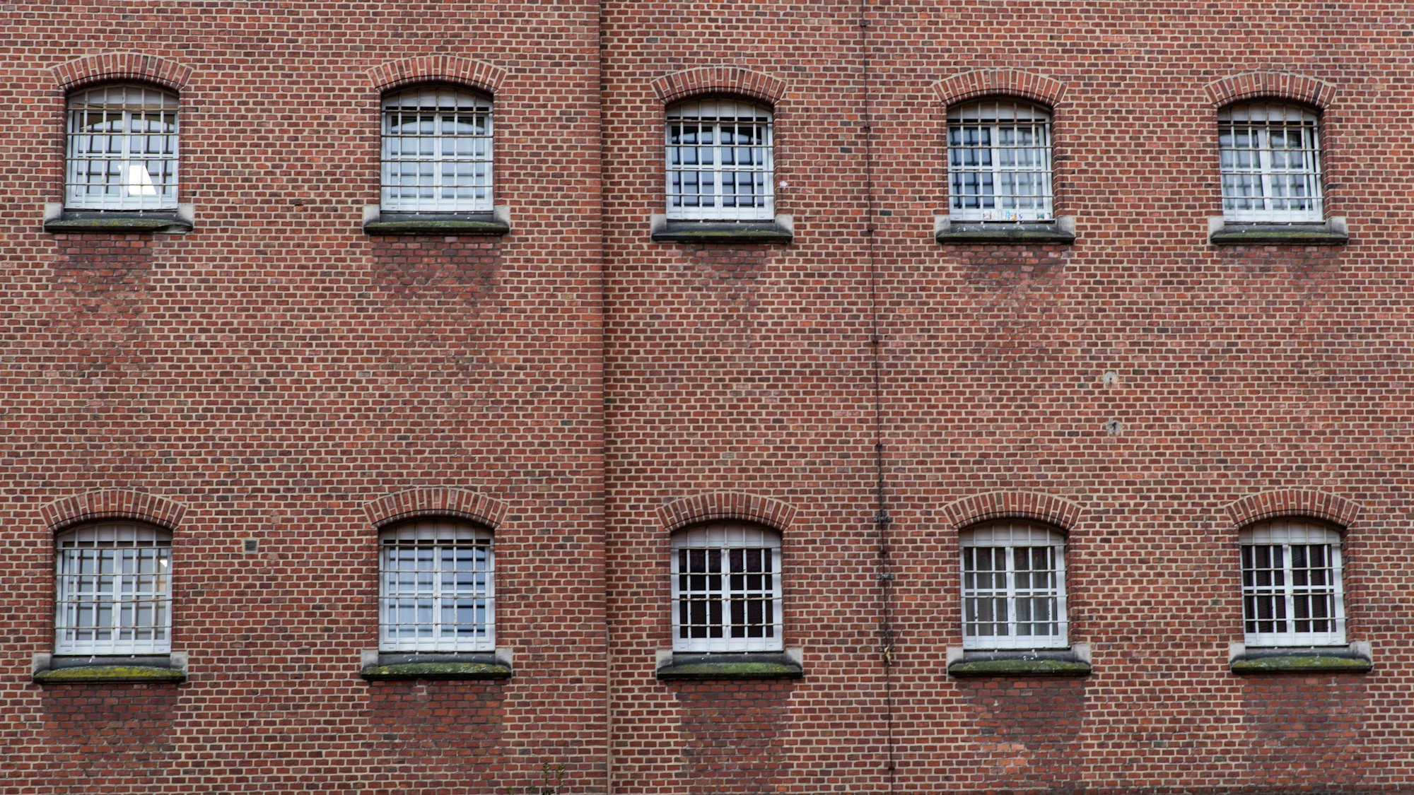 Vergitterte Fenster prägen die Fassade einer JVA. (Symbolbild)