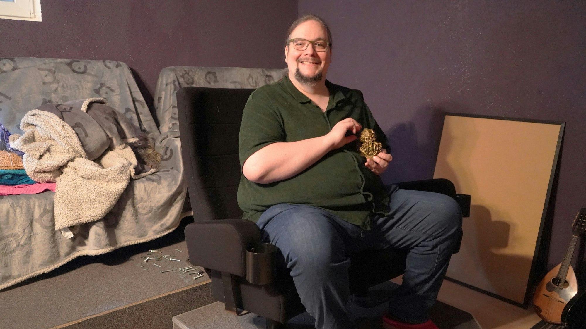 Das Foto zeigt Stefan Golsch, der die kleine Büste eines Tentakelmonsters auf einem Kinosessel zeigt.