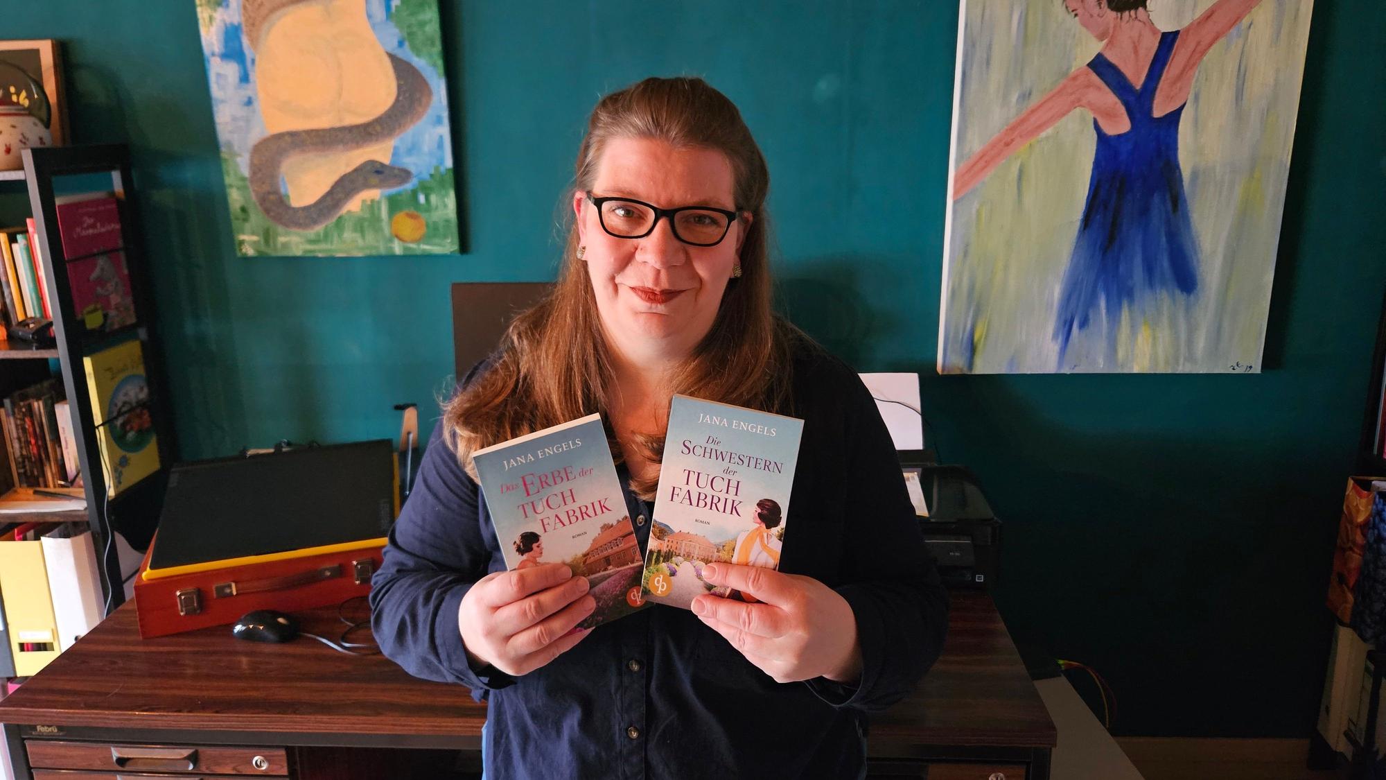 Jana Engel aus Kall steht vor ihrem Schreibtisch und hält die beiden Bücher der Tuchindustrie-Reihe in den Händen.