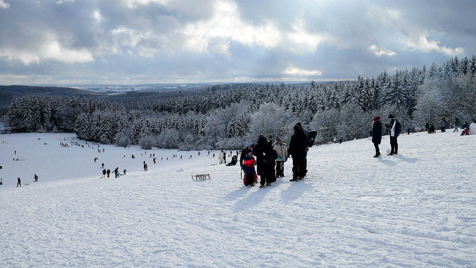 Personen auf einer Rodelpiste am Weißen Stein bei geschlossener Schneedecke.