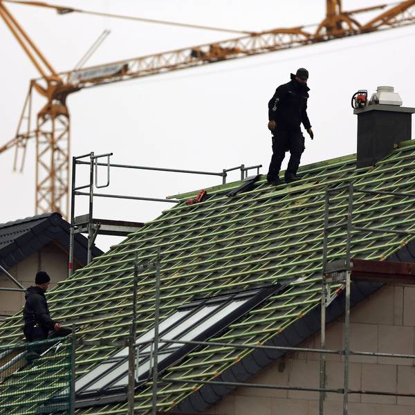 Zwei Männer arbeiten auf einem Hausdach.