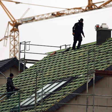 Zwei Männer arbeiten auf einem Hausdach.