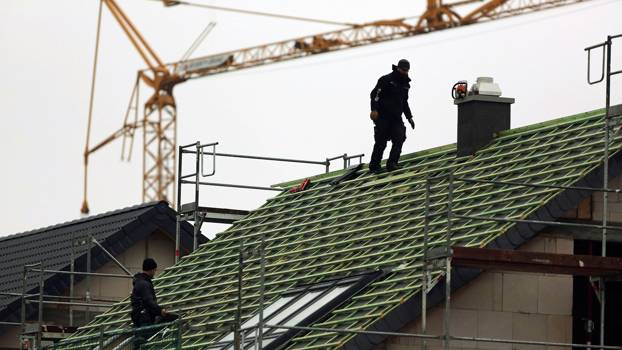 Zwei Männer arbeiten auf einem Hausdach.