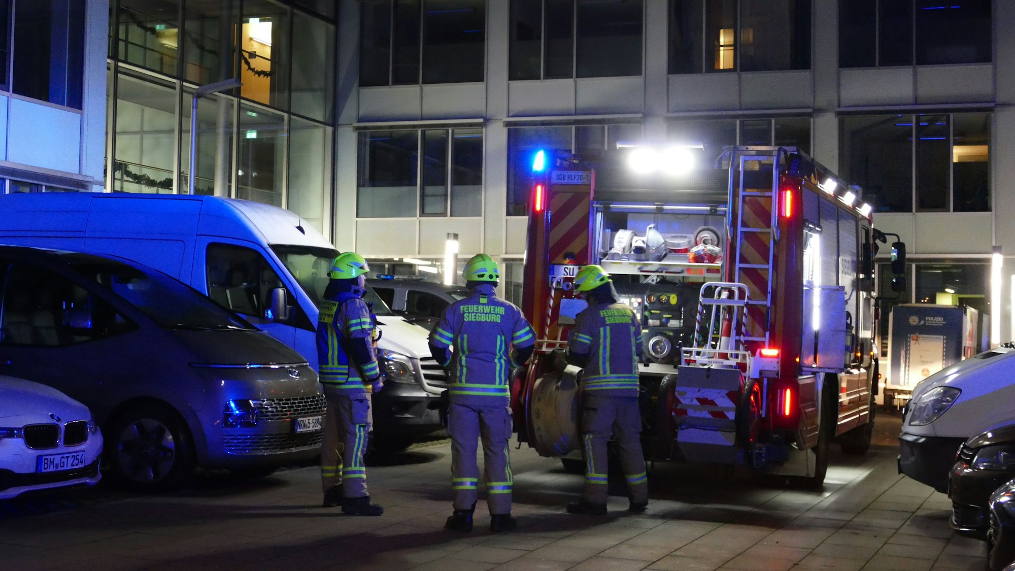 Ein Löschfahrzeug und Feuerwehrleute stehen auf dem Gelände der Siegburger Polizeiwache.