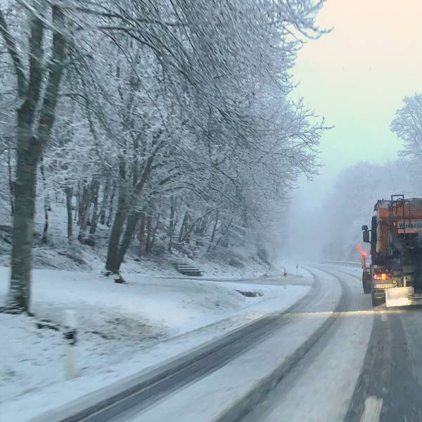 Ein Fahrzeug des Winterdienstes räumt eine verschneite Straße bei Wildenburg im Kreis Euskirchen.