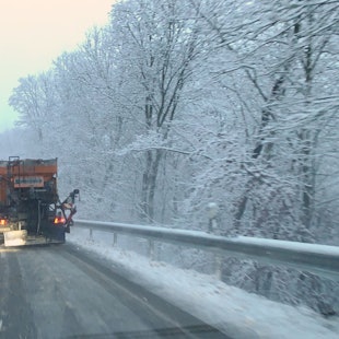 Ein Fahrzeug des Winterdienstes räumt eine verschneite Straße bei Wildenburg im Kreis Euskirchen.