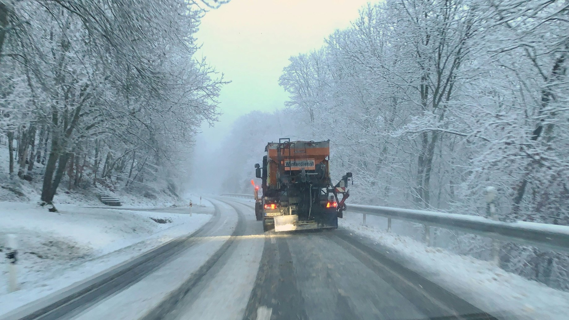 Ein Fahrzeug des Winterdienstes räumt eine verschneite Straße bei Wildenburg im Kreis Euskirchen.