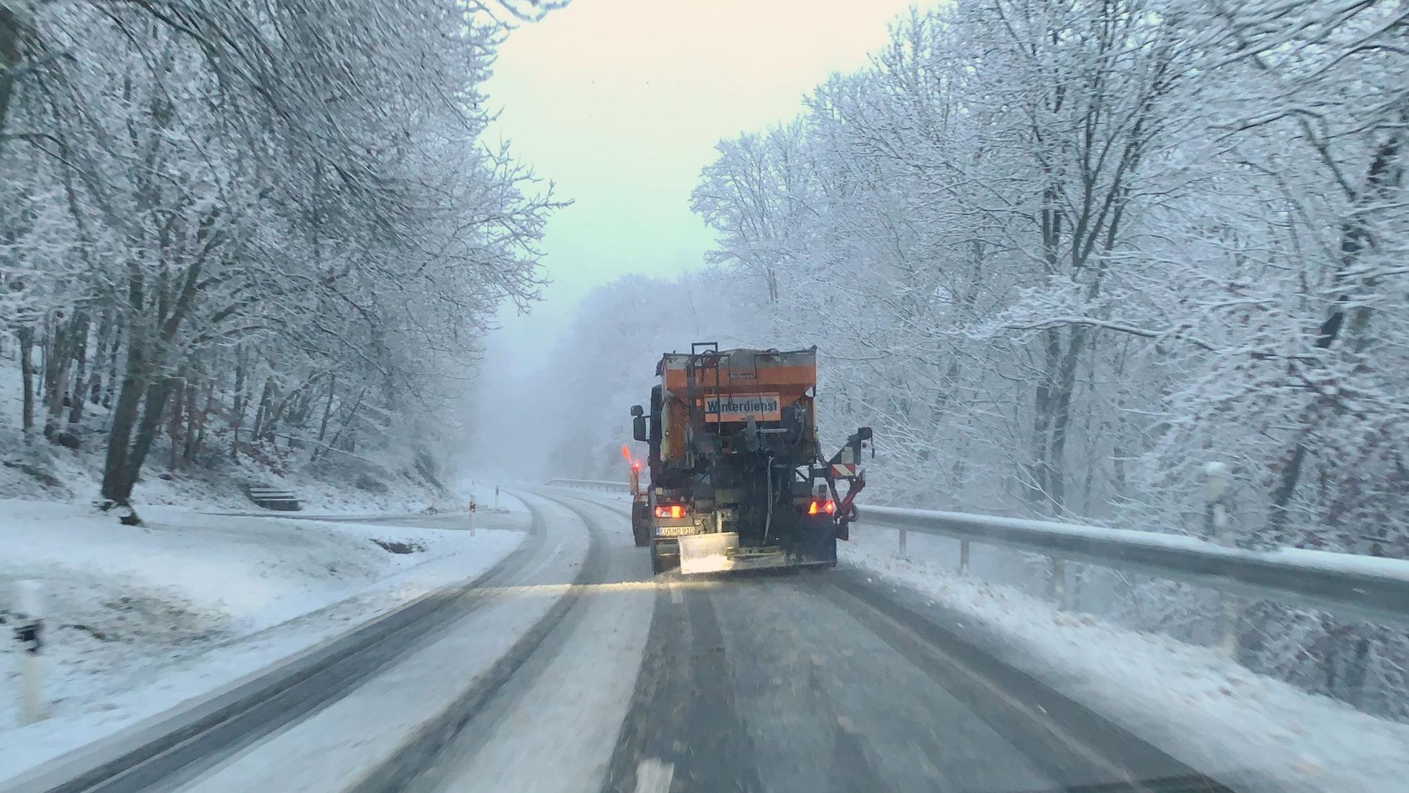 Ein Fahrzeug des Winterdienstes räumt eine verschneite Straße bei Wildenburg im Kreis Euskirchen.