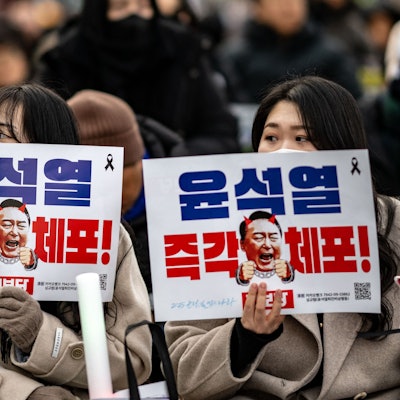 Menschen halten Plakate mit der Aufschrift „Verhaftet Yoon Suk Yeol sofort“ hoch.