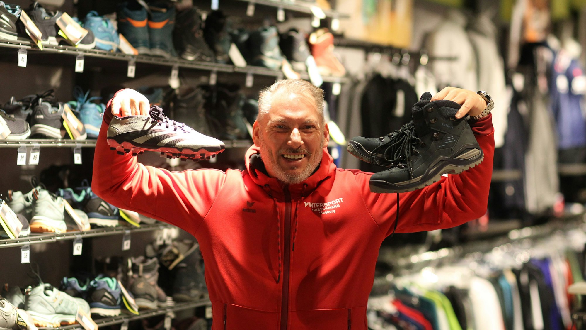 Ein Mann hält Sportschuhe in die Höhe.
