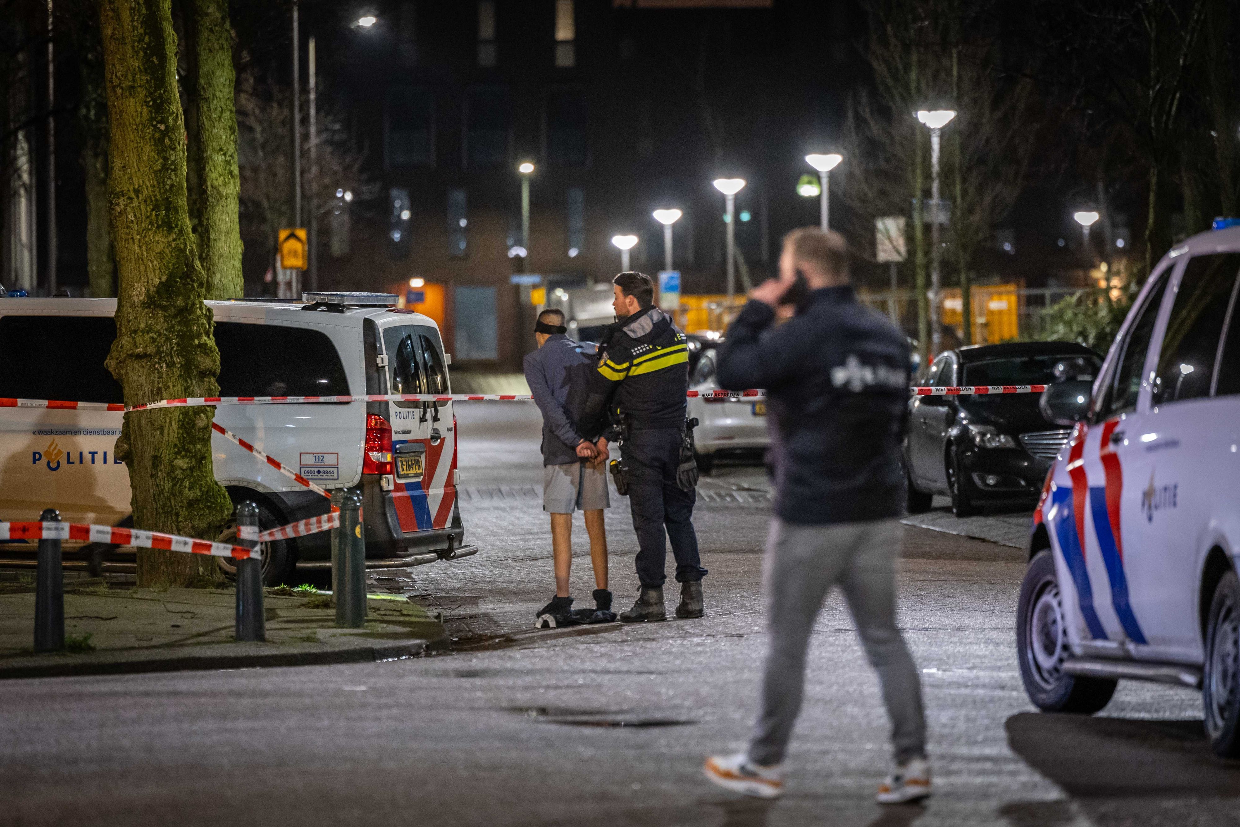 Ein Polizist nimmt einen Mann fest. Die Polizei durchsuchte ein Haus in der Speelmanstraat im Stadtteil Kralingen. Dabei wurden Schüsse abgefeuert.