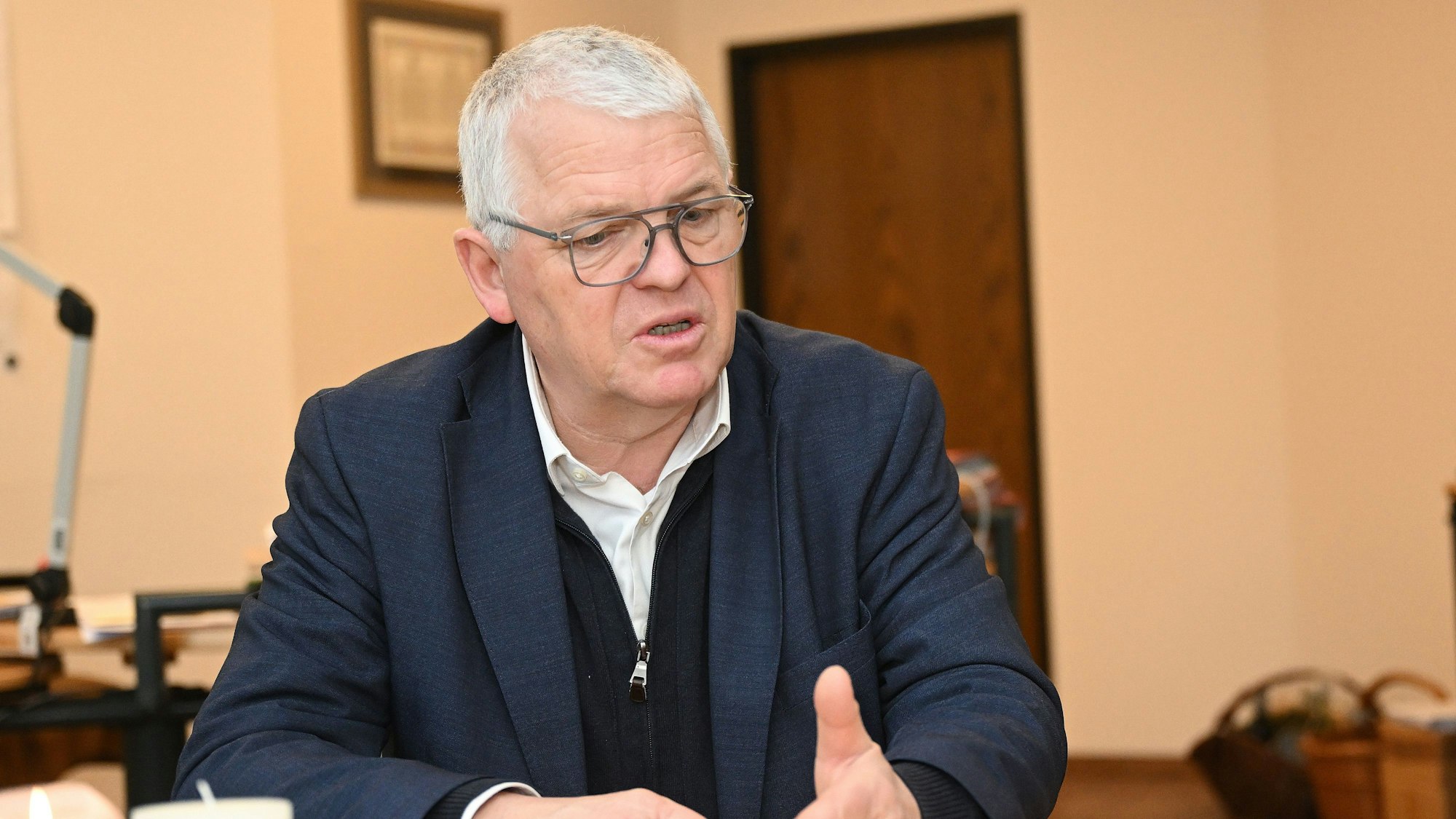 Der Kürtener Bürgermeister Willi Heider sitzt an einem Schreibtisch.