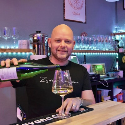 Ein kahlköpfiger Mann schenkt in der Siegburger Kneipe Zum Prinzen ein Glas Weißwein ein.