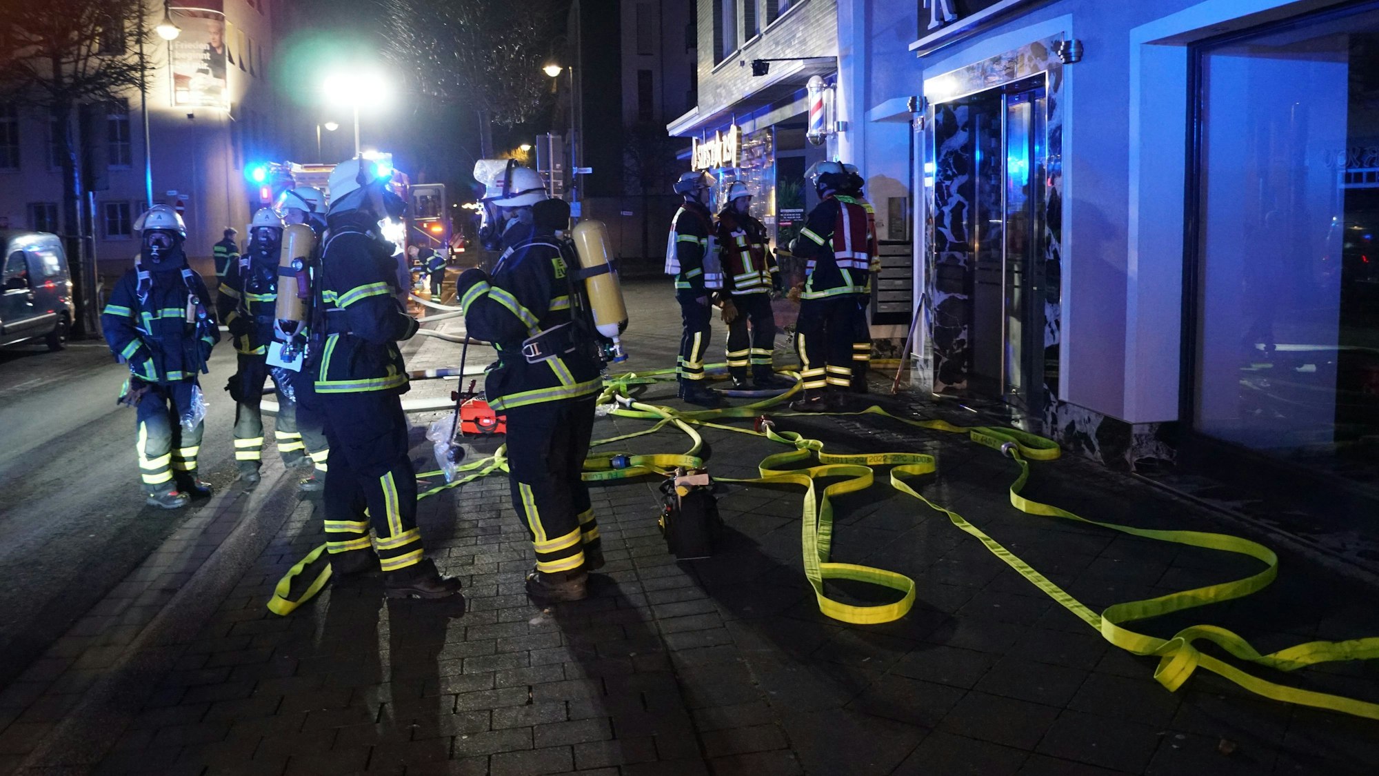 Feuerwehrleute stehen in der Dunkelheit vor dem Gebäude, in dem es gebrannt hat.