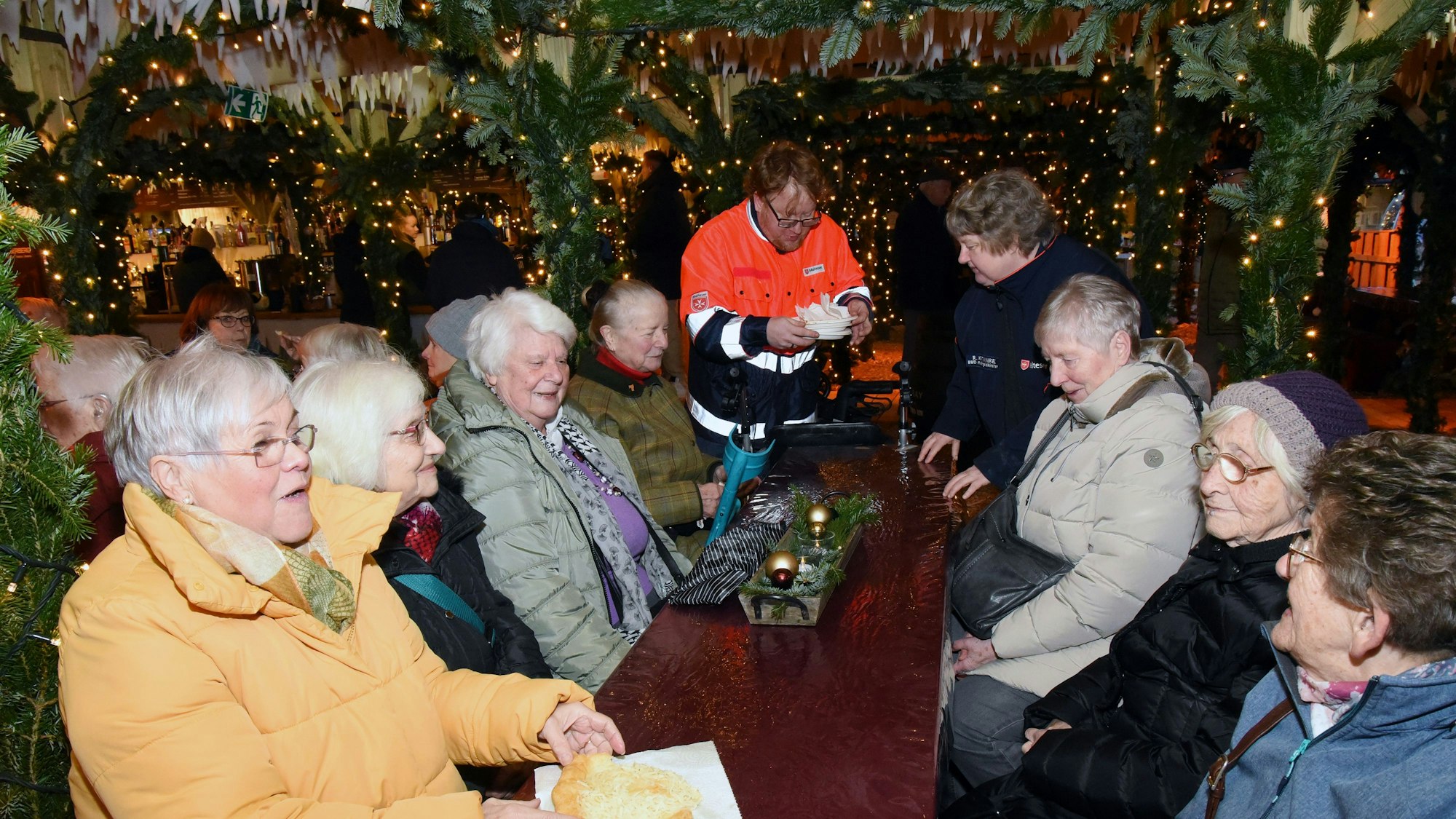 Senioren sitzen bei einem Besuch im Weihnachtsdorf in Gummersbach gemeinsam an einem Tisch.
