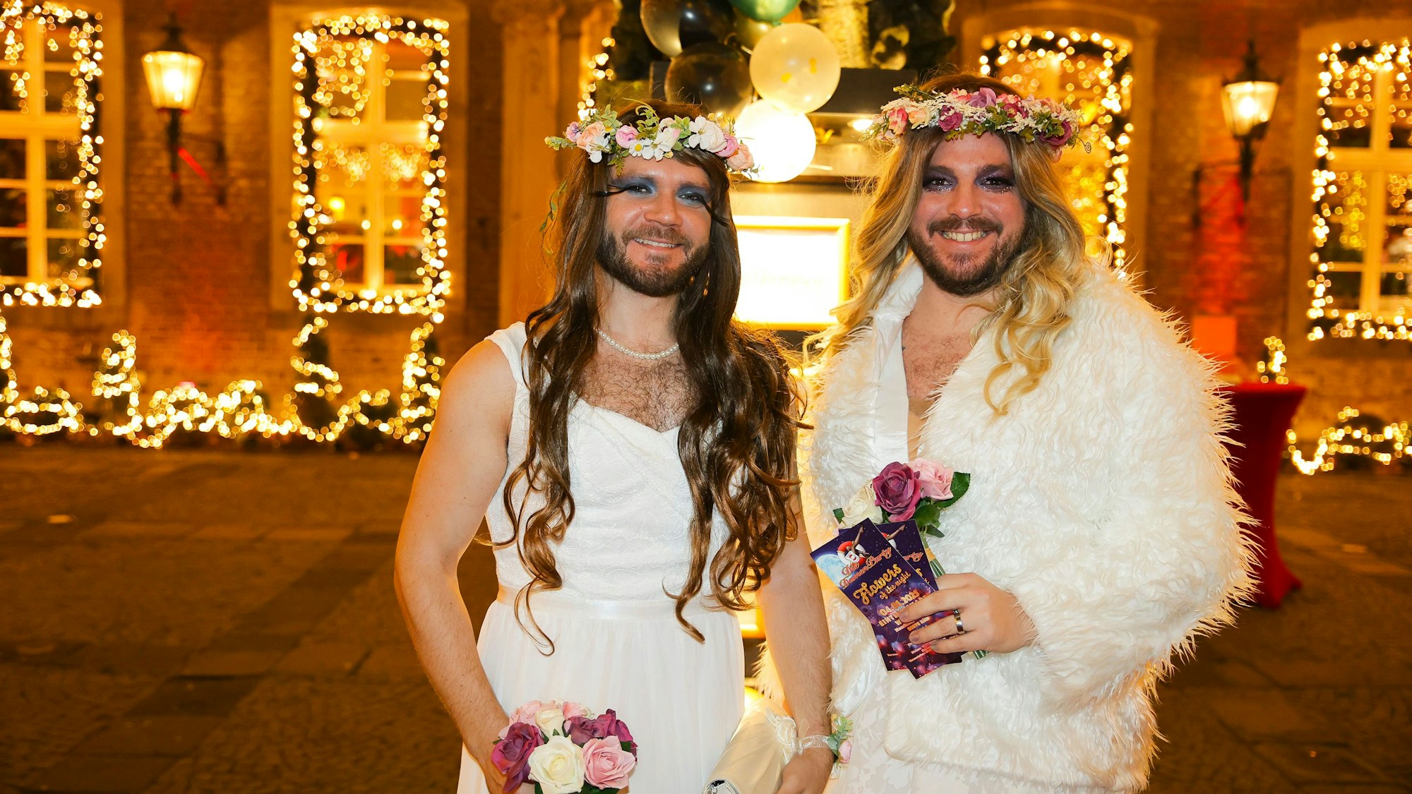 Männer mit Blumenkränzen und mit weißen Kleidern
