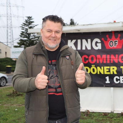 Ein Mann lächelt in die Kamera und zeigt die Geste „Daumen hoch“.