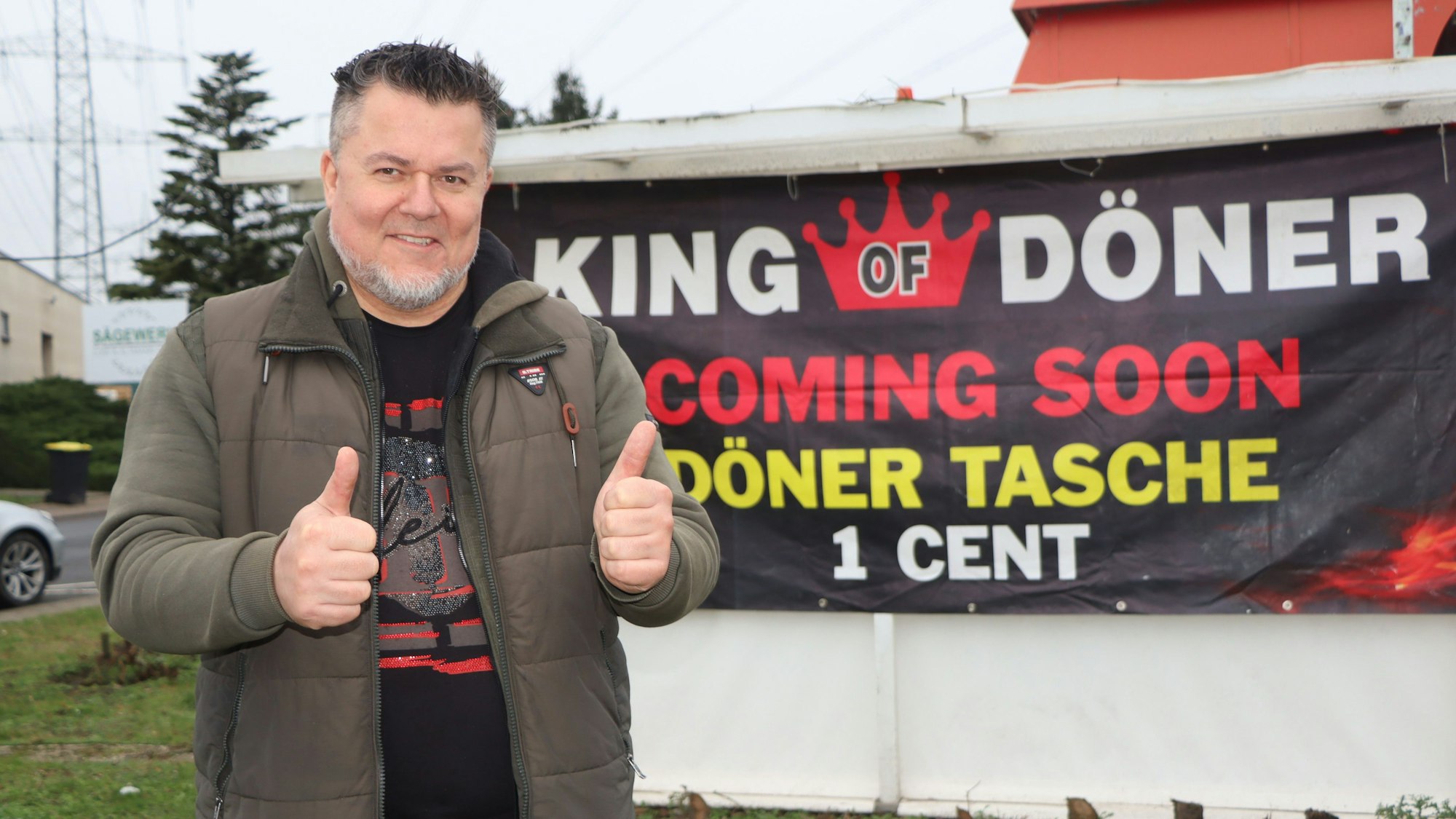 Ein Mann lächelt in die Kamera und zeigt die Geste „Daumen hoch“.