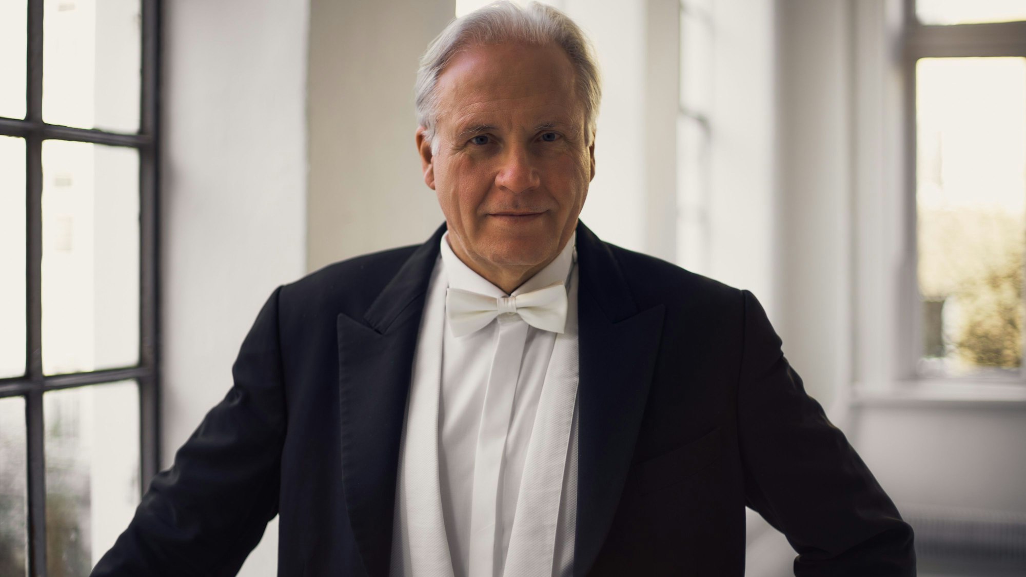 Markus Stenz trägt einen schwarzen Frack und ein weißes Hemd mit Fliege und lächelt in die Kamera.