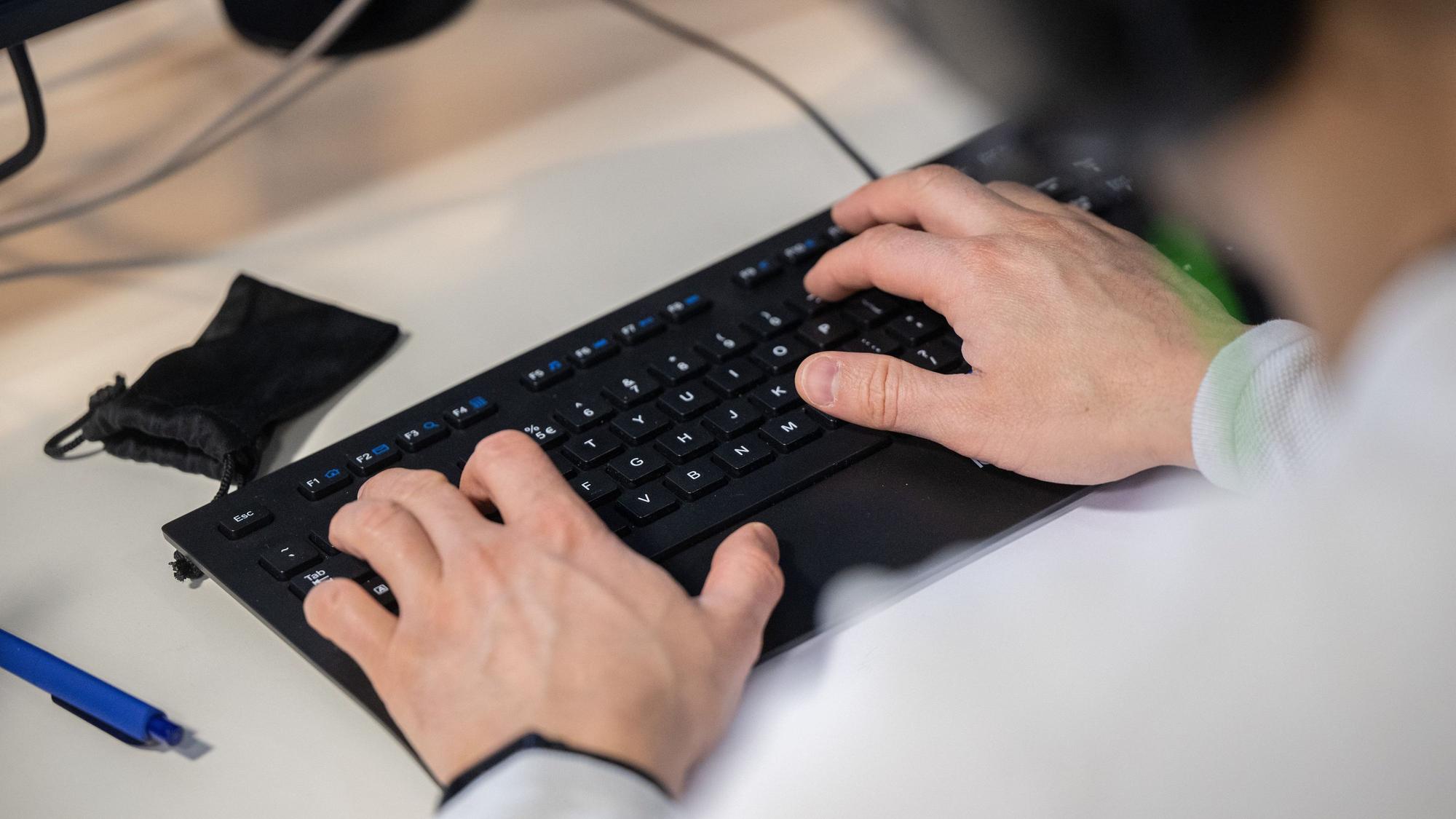 Hände tippen auf einer Computertastatur.