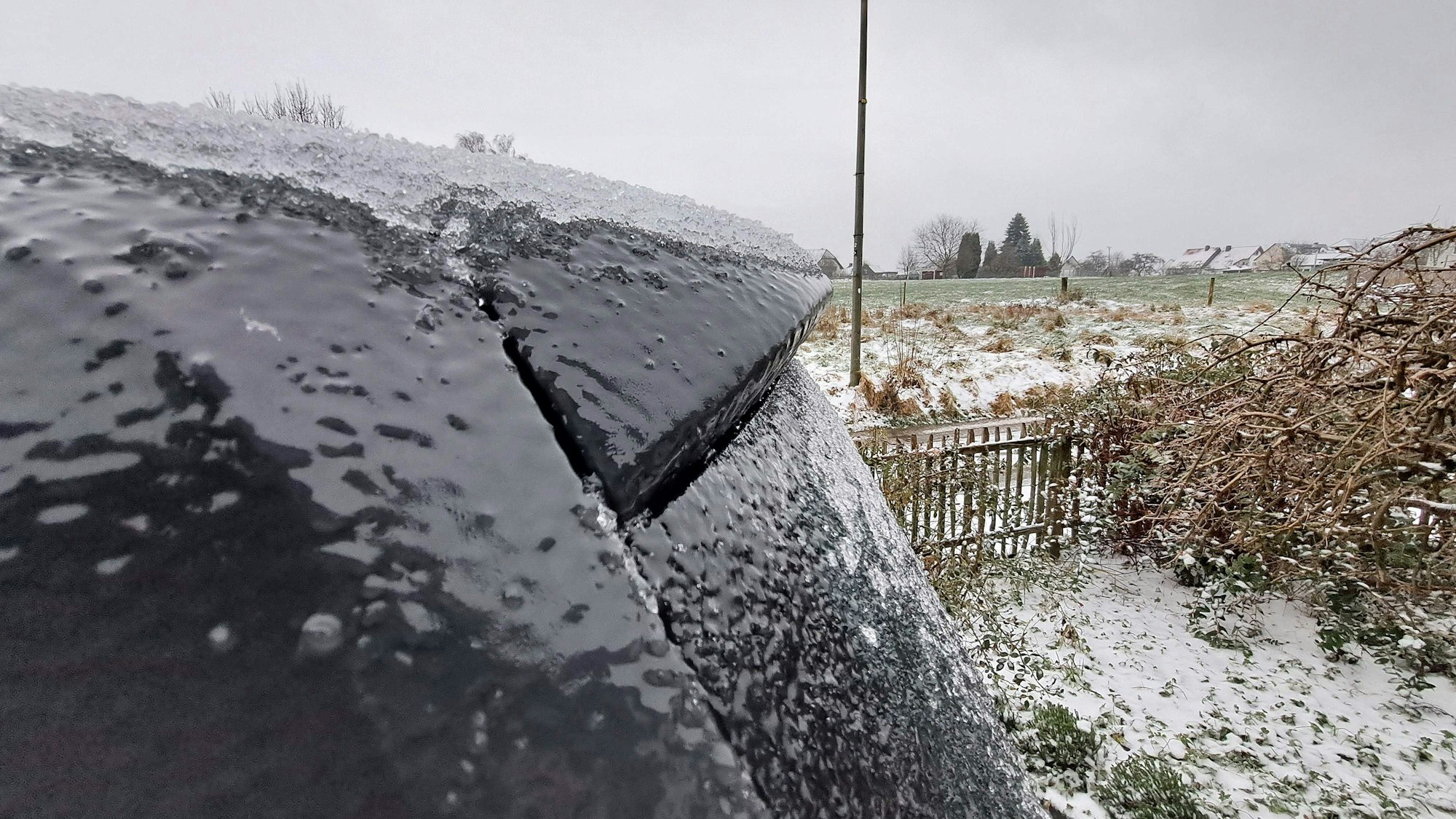 Auch einem Auto ist eine dicke Eisschicht zu sehen.