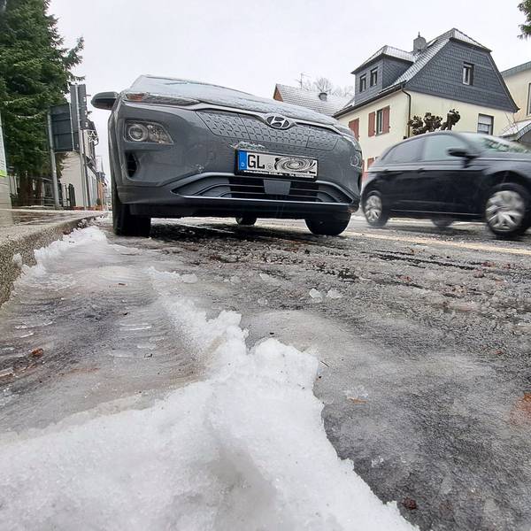 Schneematsch liegt auf der Bensberger Straße in Overath-Heiligenhaus. Autos fahren darüber.