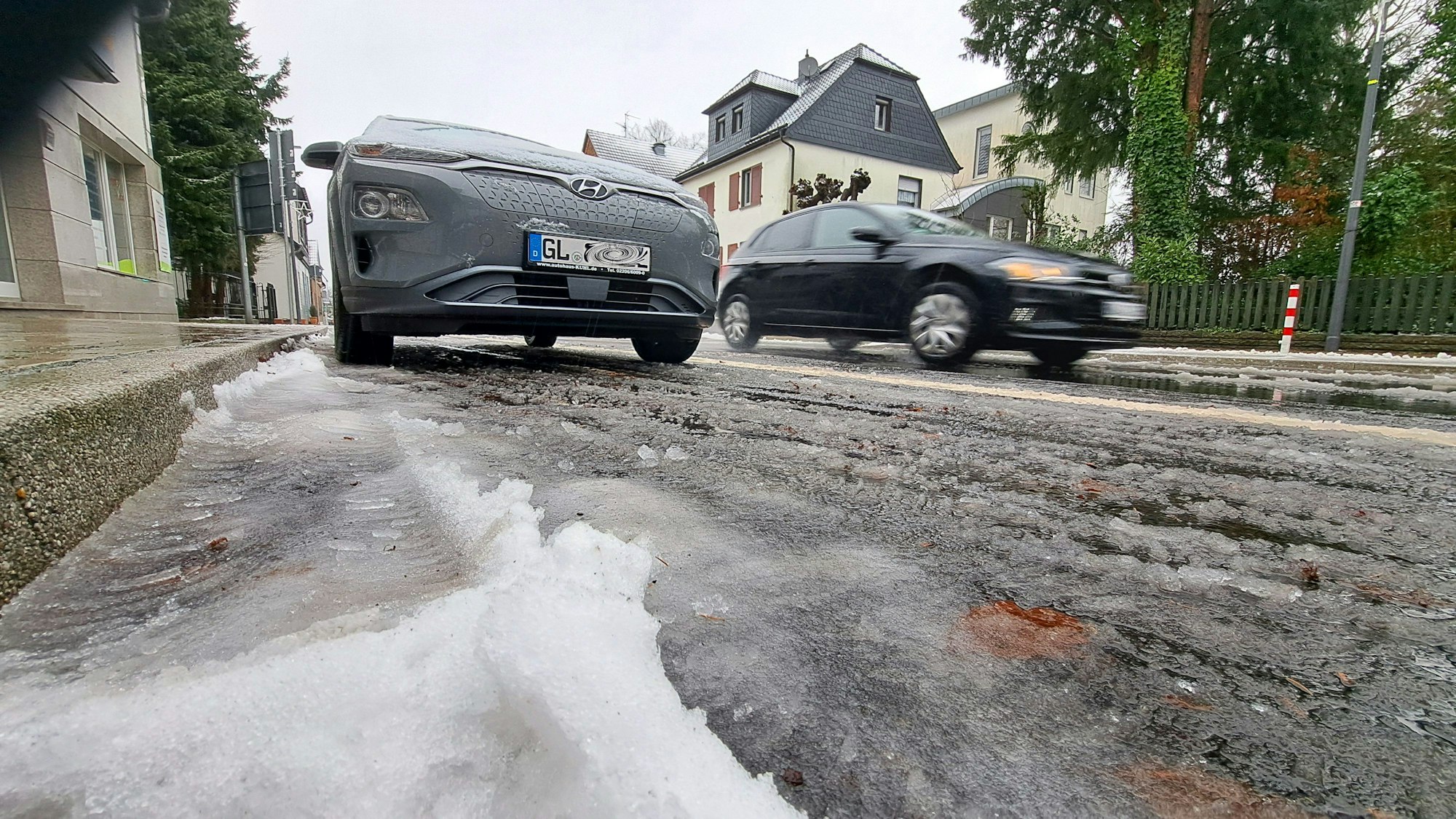 Schneematsch liegt auf der Bensberger Straße in Overath-Heiligenhaus. Autos fahren darüber.