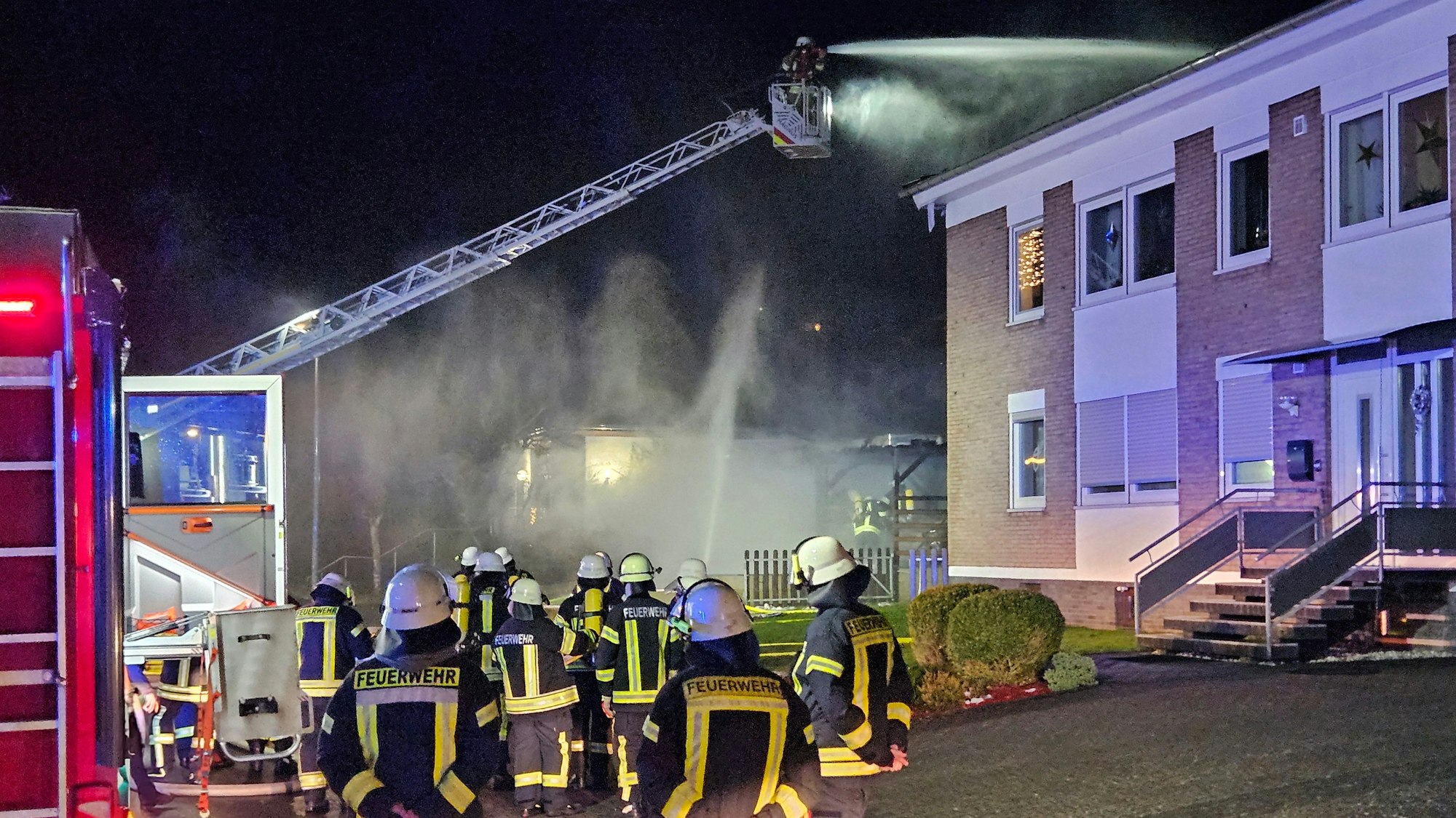 Beim Brand eines Carports in Schleiden ist die Feuerwehr mit einer Drehleiter im Einsatz.