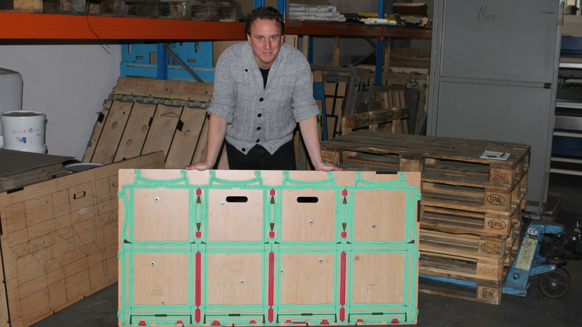 Mario Deilen steht hinter einem großen Bogen Wellpappe, der für die Weiterverarbeitung vorbereitet ist.