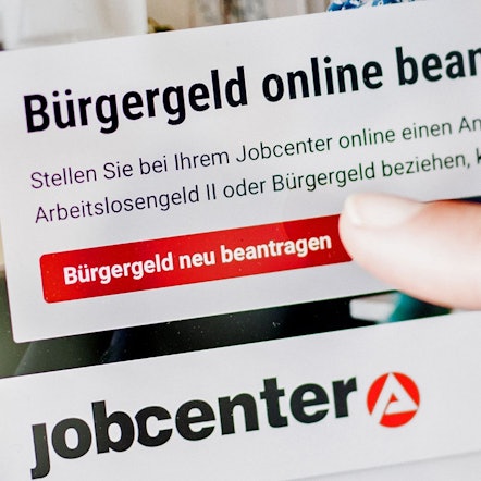 Eine Frau tippt auf einem Tablet auf einen Link zum Beantragen des Bürgergeldes im Kundenbereich im Jobcenter Berlin Mitte.