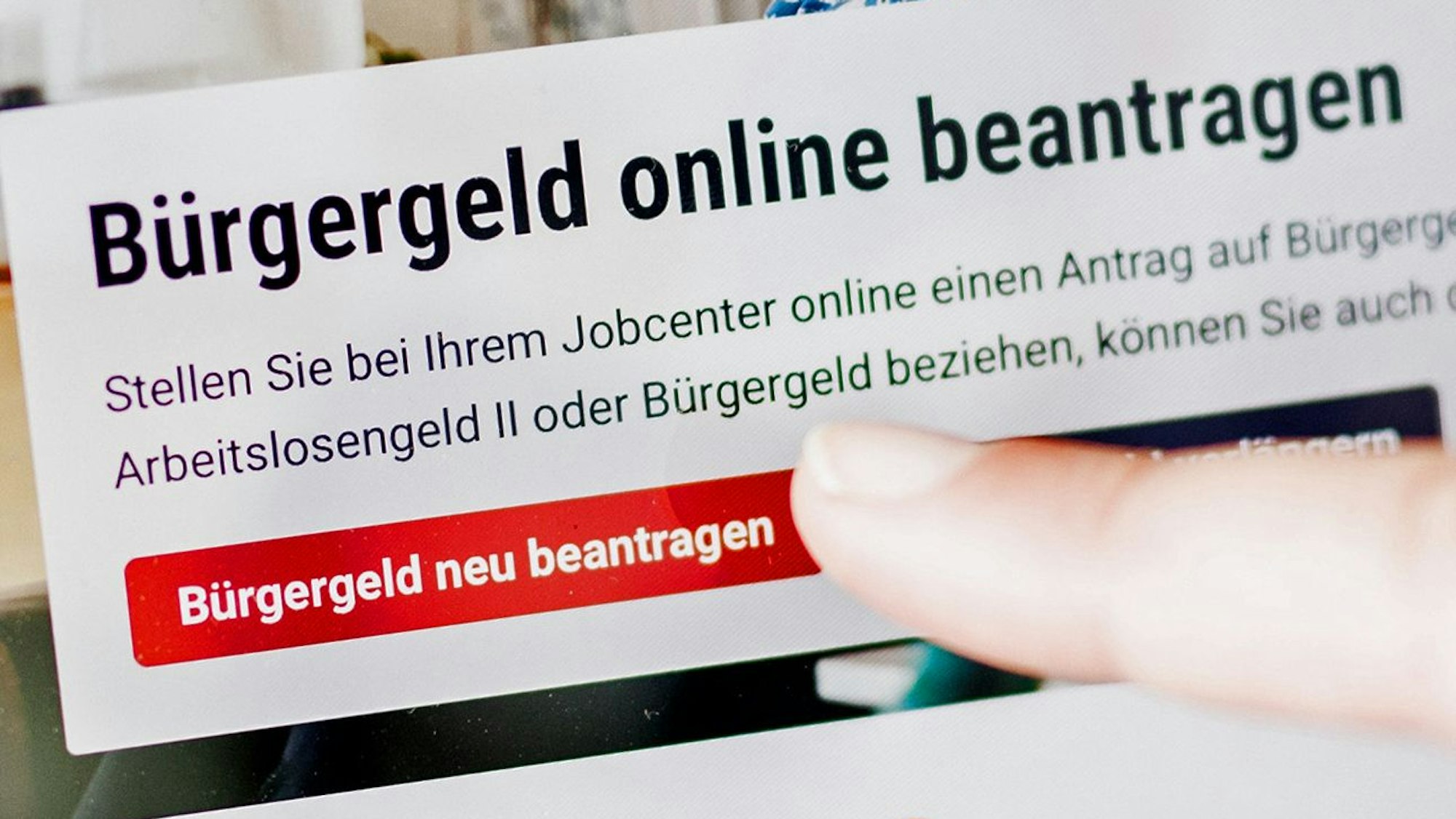 Eine Frau tippt auf einem Tablet auf einen Link zum Beantragen des Bürgergeldes im Kundenbereich im Jobcenter Berlin Mitte.