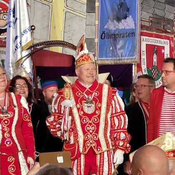 Ein Karnevalsprinzenpaar und Gefolge stehen auf einer Bühne.