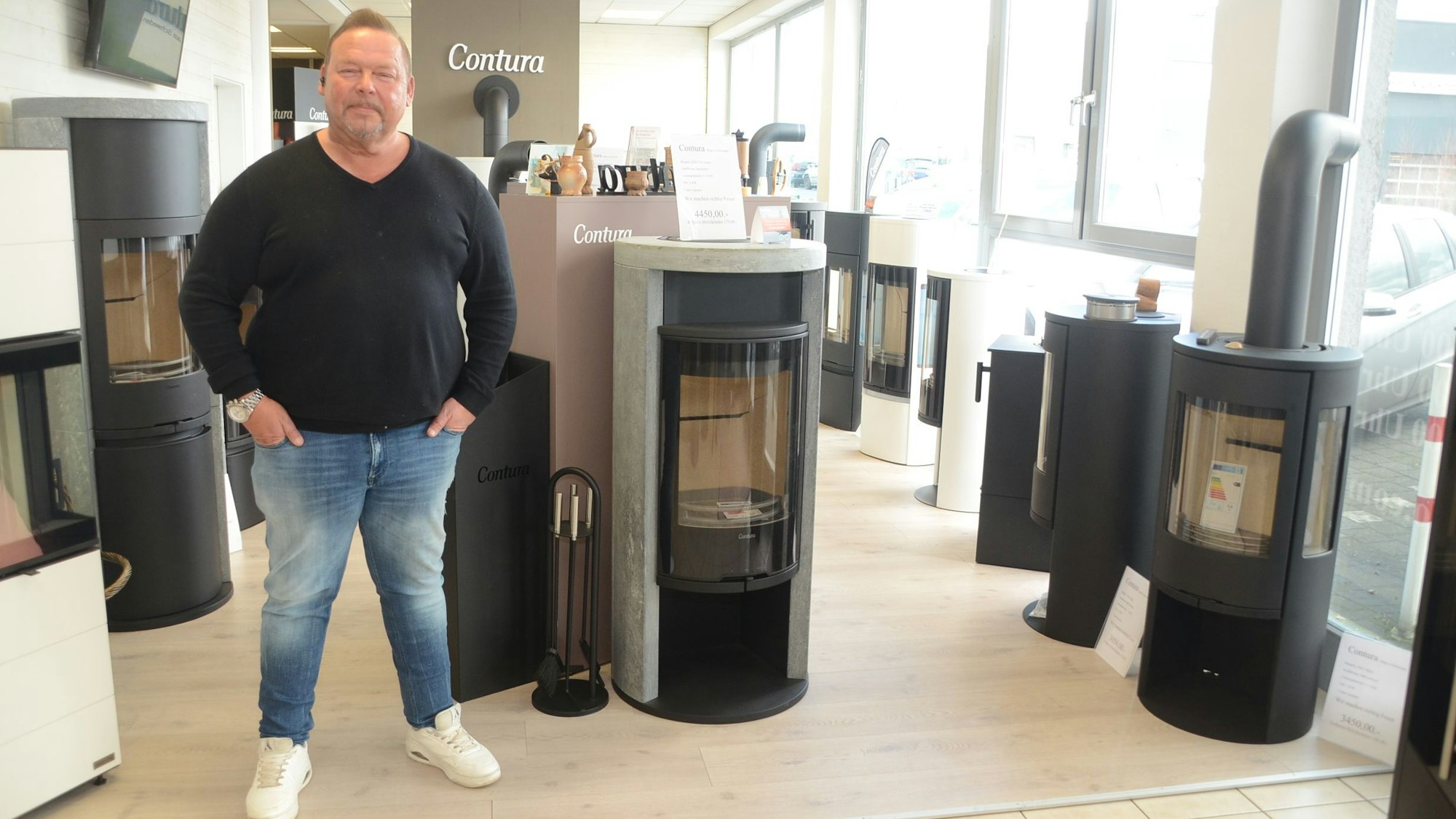 Ein Mann steht auf einer Ausstellungsfläche mit Kaminöfen.