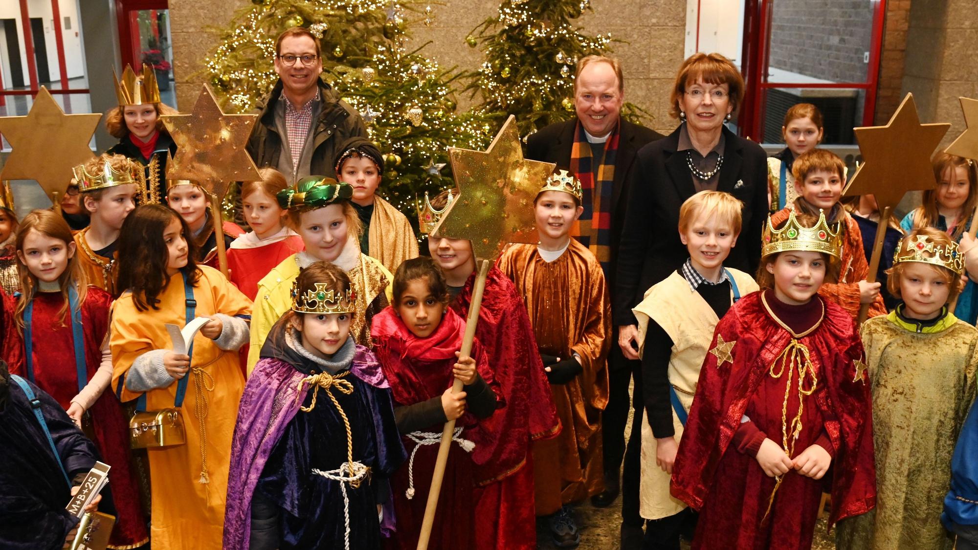 Zu sehen sind mehrere Kinder im Sternsingergewand, sowie Burkard Hofer, Monsignore Robert Kleine und Henriette Reker.